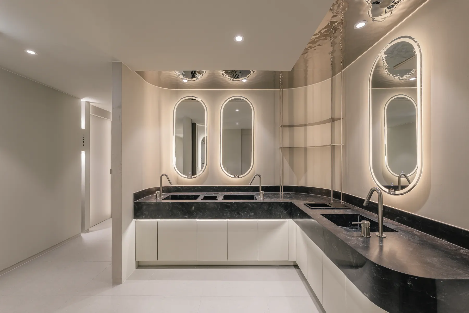 Backlit oval mirrors above a black stone counter at THE Beautiful Clinic in Seoul